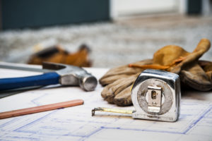 A hammer and tape measure among other tools on a construction site workbench. The Role of Construction in Economic Growth and Recovery